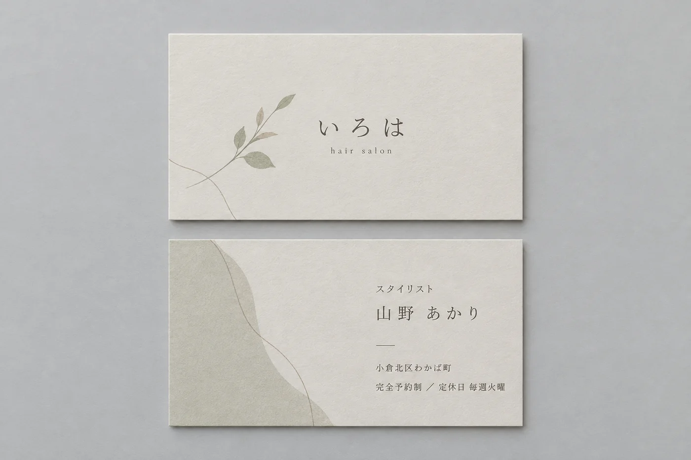 美容室の名刺の表と裏。淡いベージュの紙に、葉の線画と店名、裏にスタイリストの名前と予約制の案内